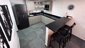 A compact kitchen with a refrigerator, microwave, and sink. There is a small dining area with two chairs and a table. - Amplio apt en poblado by Hoost APT 701 (Medellín)