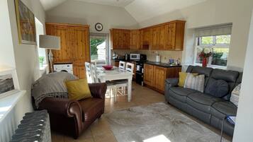 A spacious living area with a dining table, sofa, and kitchen in the background.