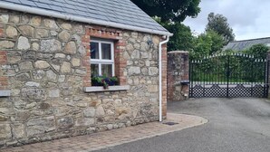 A stone building with a window and a black metal gate. - Cottage in the Dublin Mountain (Cunard)