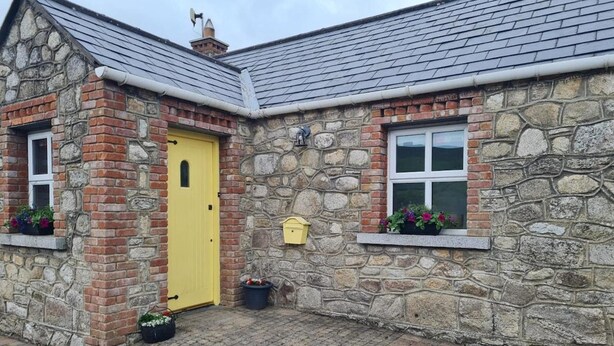 A stone house with a yellow door, a small mailbox, and flower boxes on the windowsills. - Cottage in the Dublin Mountain (Cunard)