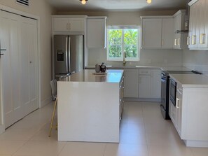 Una cocina moderna con armarios blancos, electrodomésticos de acero inoxidable y una isla central.