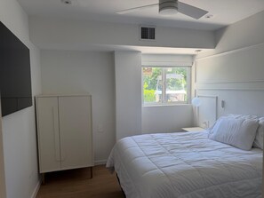 A bedroom with a bed, a wardrobe, a window, and a ceiling fan.
