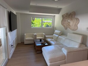 Una sala de estar moderna con un sofá seccional, una mesa de centro y un televisor de pantalla plana montado en la pared.