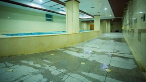 A corridor with tiled flooring, a pool area with blue tiles, and a tiled wall. - Jixibeifu Hotel (Jixi)