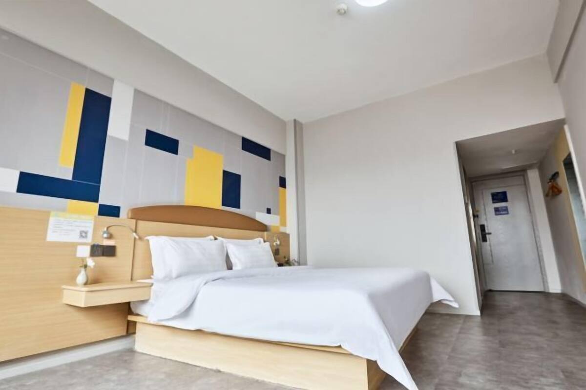 A hotel room with a bed, bedside table, and a wall with geometric patterns.