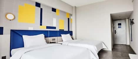 Een hotelkamer met twee bedden, een modern hoofdbord, een klein nachtkastje en een ronde wandlamp.