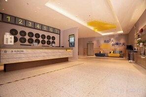 Un'area della reception di un hotel, con scrivania, parete con orologi e zona salotto.