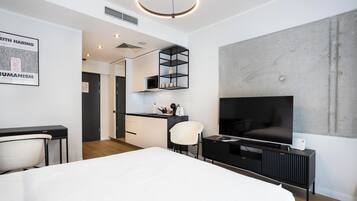 Een moderne hotelkamer met een groot bed, een televisie, een bureau en een kitchenette.