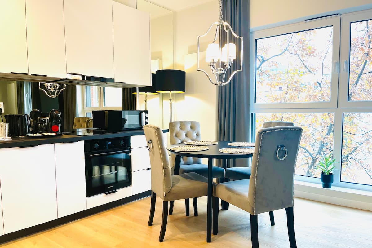 Una cocina moderna con armarios blancos, encimera negra y un comedor con mesa y sillas.