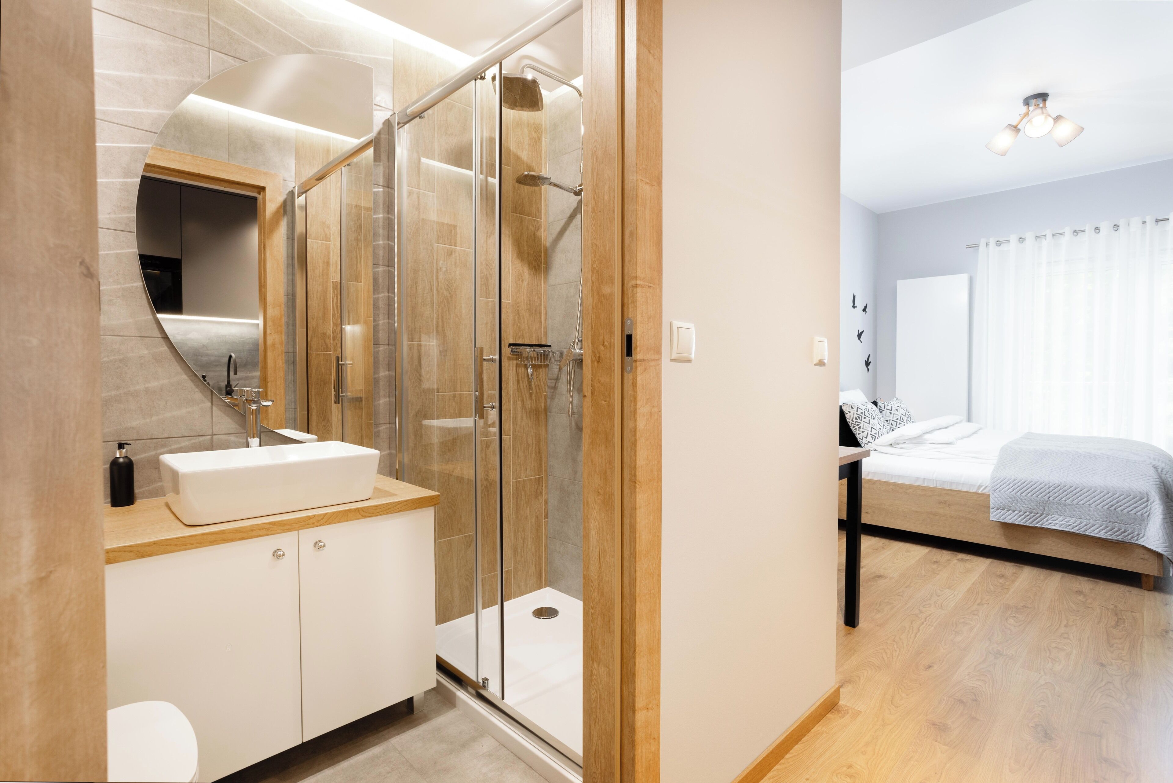 A modern bathroom with a glass shower enclosure, a wooden vanity, and a white sink.