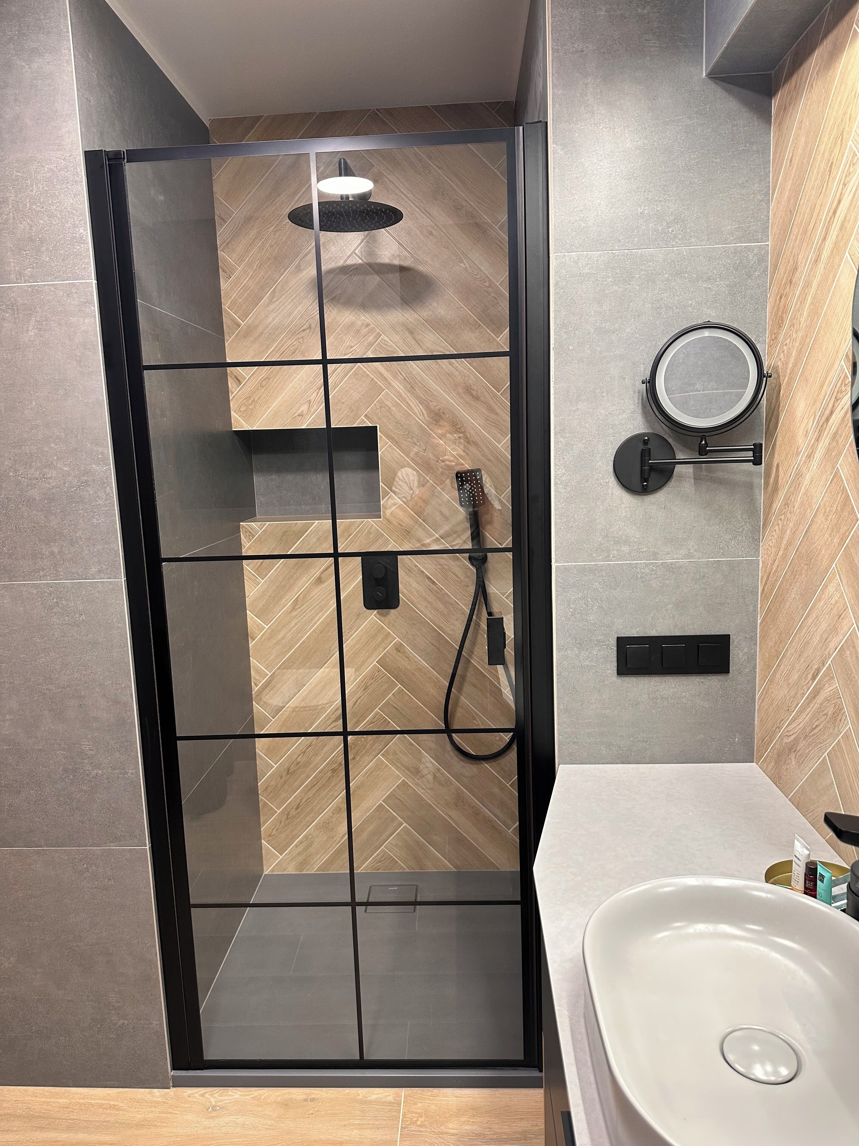 A modern bathroom with a glass-enclosed shower, a sink, and a mirror.