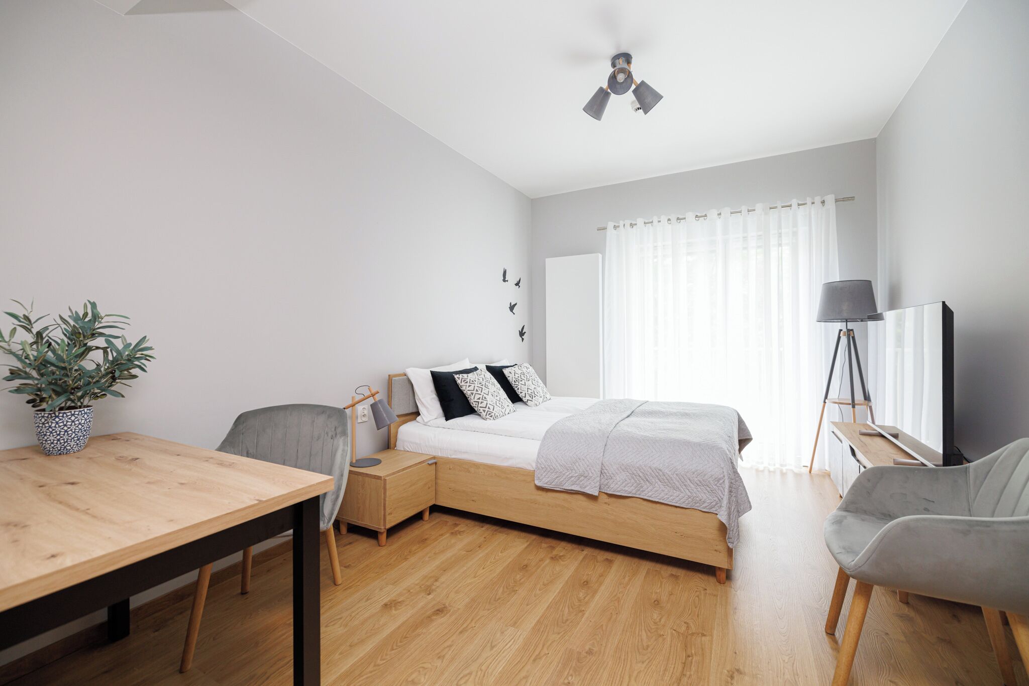 Une chambre à coucher moderne avec un lit, une table de chevet, une lampe et une plante en pot.