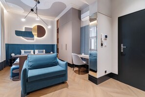 Une chambre d’hôtel moderne avec un canapé bleu, un bureau et un miroir.