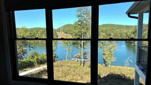 A view through a window of a lake, surrounded by trees and a dock. - Brand new luxury craftsman. 5000 sqft with 5 bedrooms, 5 baths and bunk room. (Six Mile)