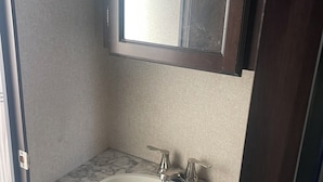 Ein Badezimmer mit Marmorwaschbecken, einem Spiegel und einem Holzkabinent.