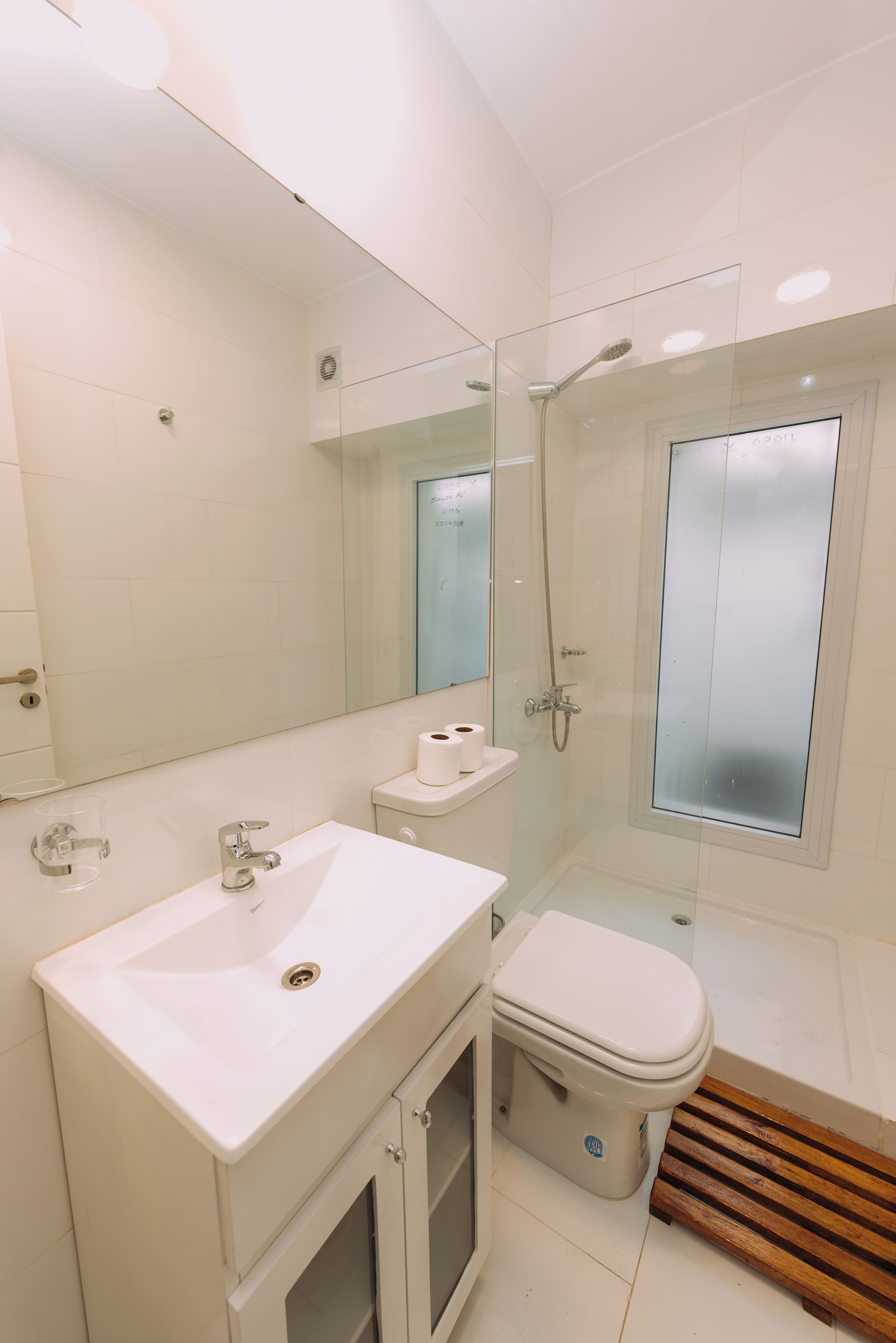 A modern bathroom with a white sink, toilet, and glass-enclosed shower.