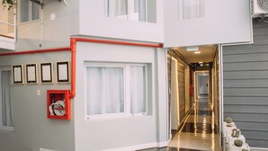 A modern interior with a hallway leading to a door, a fire hose reel, and a row of potted plants. - Maison Work & Travel 2 - Palermo  (Buenos Aires)