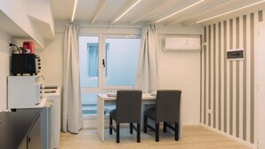 A compact kitchen with a dining area, a built-in oven, and a window with curtains. - Maison Work & Travel 2 - Palermo  (Buenos Aires)