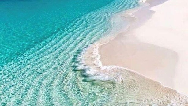 Una playa con agua turquesa cristalina y arena blanca.