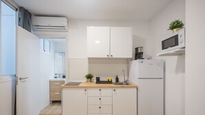 A compact kitchen with white cabinets, a wooden countertop, a microwave, a refrigerator, and a small sink.
