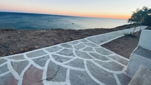 Ein Küstenweg, der zum Meer führt, mit blauem Himmel.