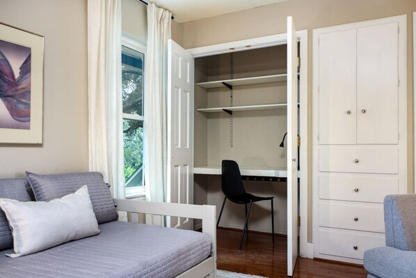 A bedroom with a bed, a desk, and a wardrobe.