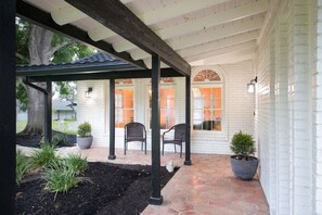 A covered patio with brick flooring, white brick walls, and a pergola structure. - Casa Blanca Estate: Lux 5BR/4BA (San Antonio)
