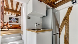 A kitchen with a built-in sink, stainless steel appliances, and exposed wooden beams.