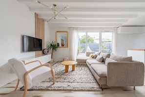 A modern living room with a sofa, chairs, a TV, and a large window.
