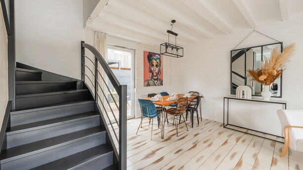 A modern interior with a staircase, dining area, and a large mirror.