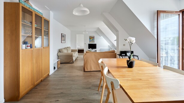 Un vaste espace de vie comprenant une table à manger en bois, un canapé et un téléviseur en arrière-plan.