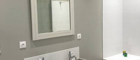 A bathroom with two sinks, a mirror, and a bathtub.