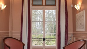 Una habitación con suelo de parqué tipo espiga, un doble acceso con paneles de vidrio y dos sillones tapizados en rosa.