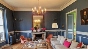 Una sala de estar con chimenea, candelabro y un espejo grande.