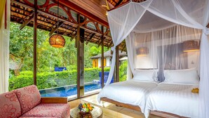 Une chambre avec un grand lit, un canapé et une vue sur une piscine.