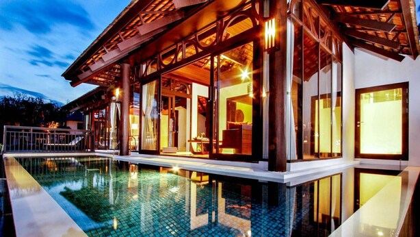 Een modern huis met een zwembad, grote ramen en een houten terras.