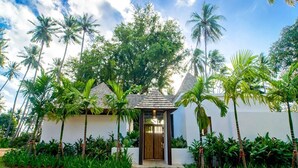 A house with a wooden door, surrounded by lush greenery and palm trees. - The Vijitt Resort - Vijitt Pool Villa (Rawai)
