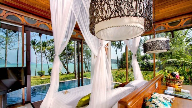 A bedroom with a view of the ocean, a canopy bed, a television, and a bedside table with a basket of fruit. - The Vijitt Resort - Vijitt Pool Villa (Rawai)