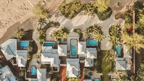 Eine Luftaufnahme eines Resorts mit mehreren Schwimmbecken, Palmen und einem Sandstrand.
