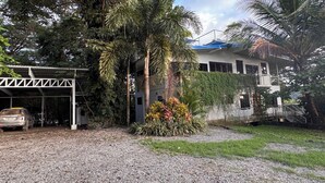 Ein Gebäude mit überdachtem Parkbereich, umgeben von dichter Vegetation und Palmen.