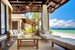 A beachside lounge with a glass table, cushioned seating, and a view of the ocean. - Harlan Beach Villa Boracay (Boracay Island)