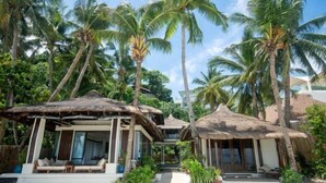 A resort with thatched-roof structures, palm trees, and a clear sky. - Harlan Beach Villa Boracay (Boracay Island)