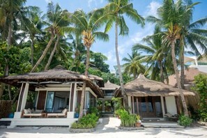 A resort with thatched-roof structures, palm trees, and a clear sky. - Harlan Beach Villa Boracay (Boracay Island)