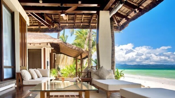 A beachside lounge with a glass table, cushioned seating, and a view of the ocean. - Harlan Beach Villa Boracay (Boracay Island)
