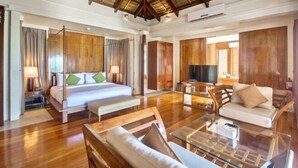 A spacious room with a bed, a sofa, a glass coffee table, and wooden flooring. - Harlan Beach Villa Boracay (Boracay Island)