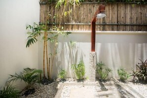 A bamboo fence, a concrete pathway, and various plants in a garden area. - Harlan Beach Villa Boracay (Boracay Island)