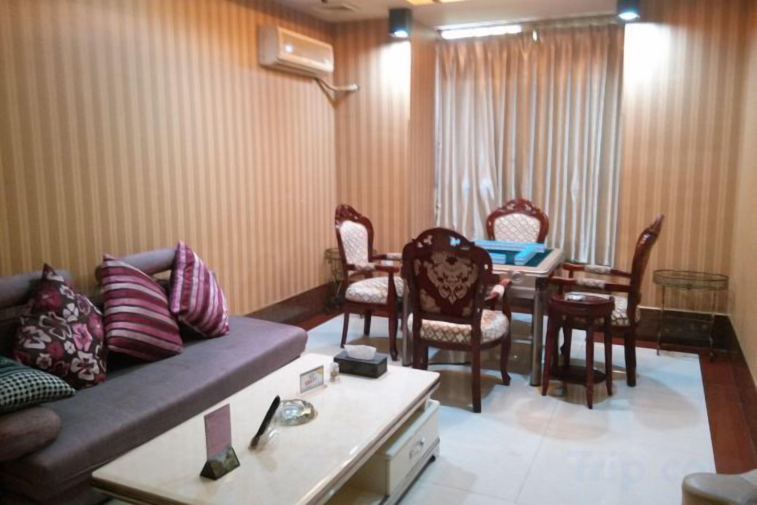 A living room with a sofa, a coffee table, and a dining area with chairs and a table.