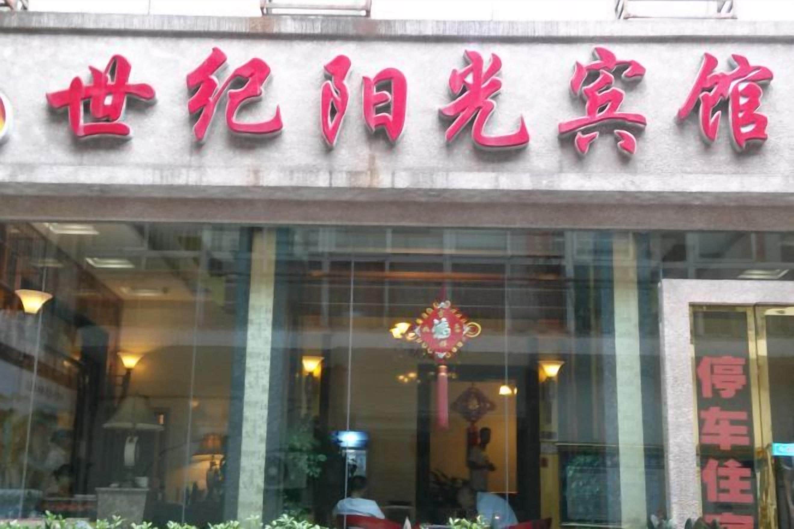 Un bâtiment avec une enseigne en caractères chinois, une entrée en verre et un intérieur visible, agrémenté d’un lustre.