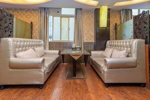 A room with two leather sofas, a glass table, and a window with curtains.