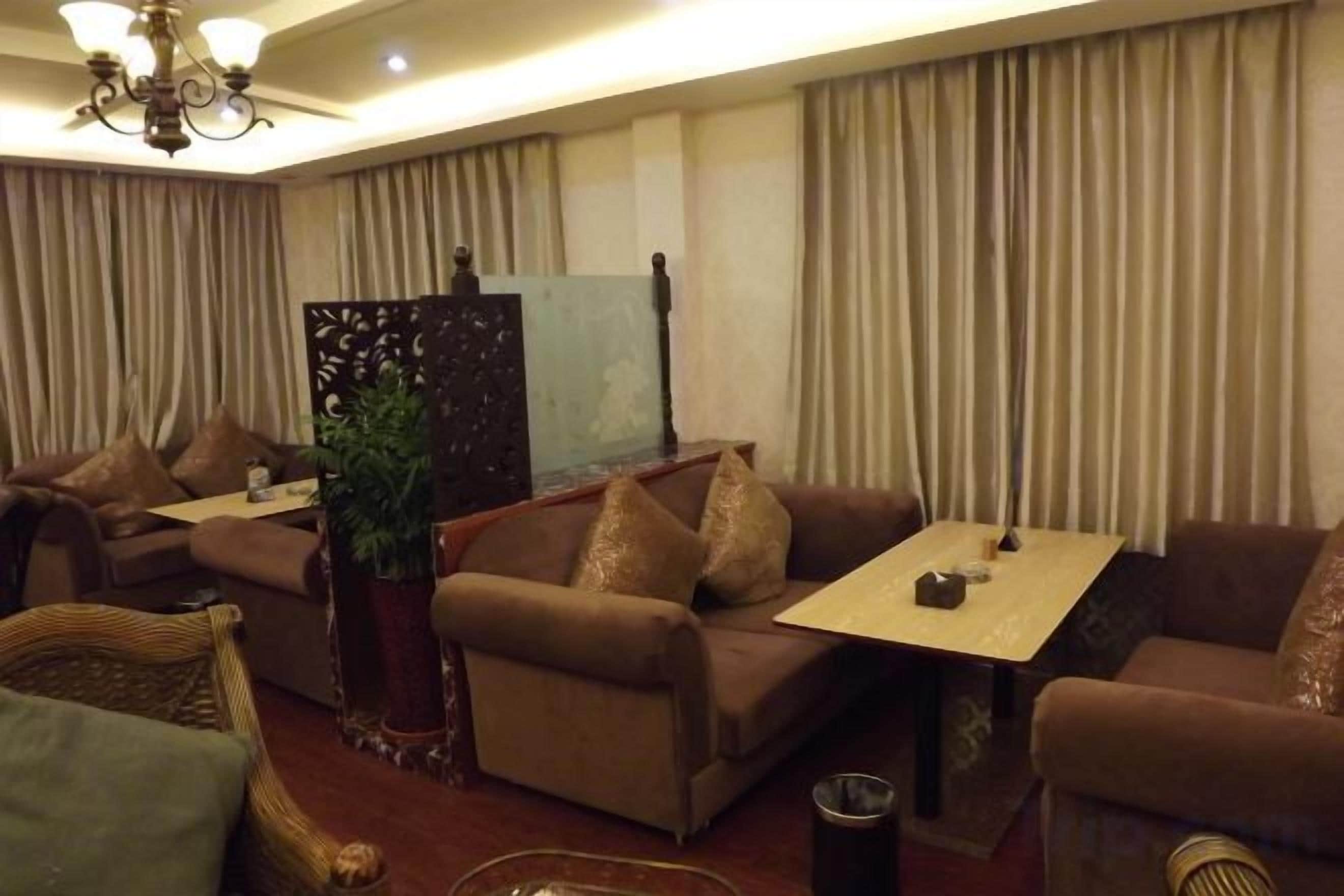 Une chambre d’hôtel avec un canapé, une petite table et une plante décorative.